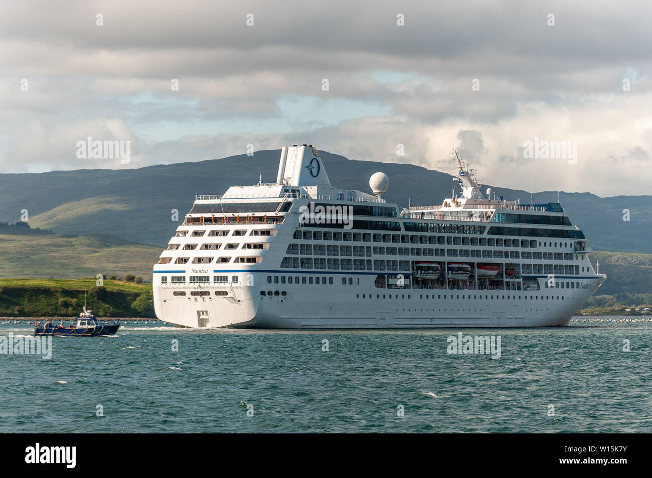 Bantry, West Cork, Irlanda. Il 30 giugno, 2019. Per la seconda volta in una settimana, la nave da crociera "Nautica" ha trascorso la giornata ancorato nel porto di Bantry. Ella è raffigurato di salpare per Galway come Whiddy Island Ferry passa, voce per Bantry. Credito: Andy Gibson/Alamy Live News. Foto Stock