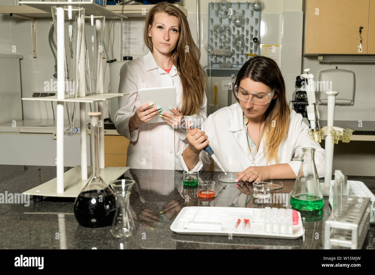 Team di due, bianco caucasico, femmina tecnici di laboratorio in bianche vesti lavorando in chimica o laboratorio farmaceutico, e attrezzature da laboratorio Foto Stock