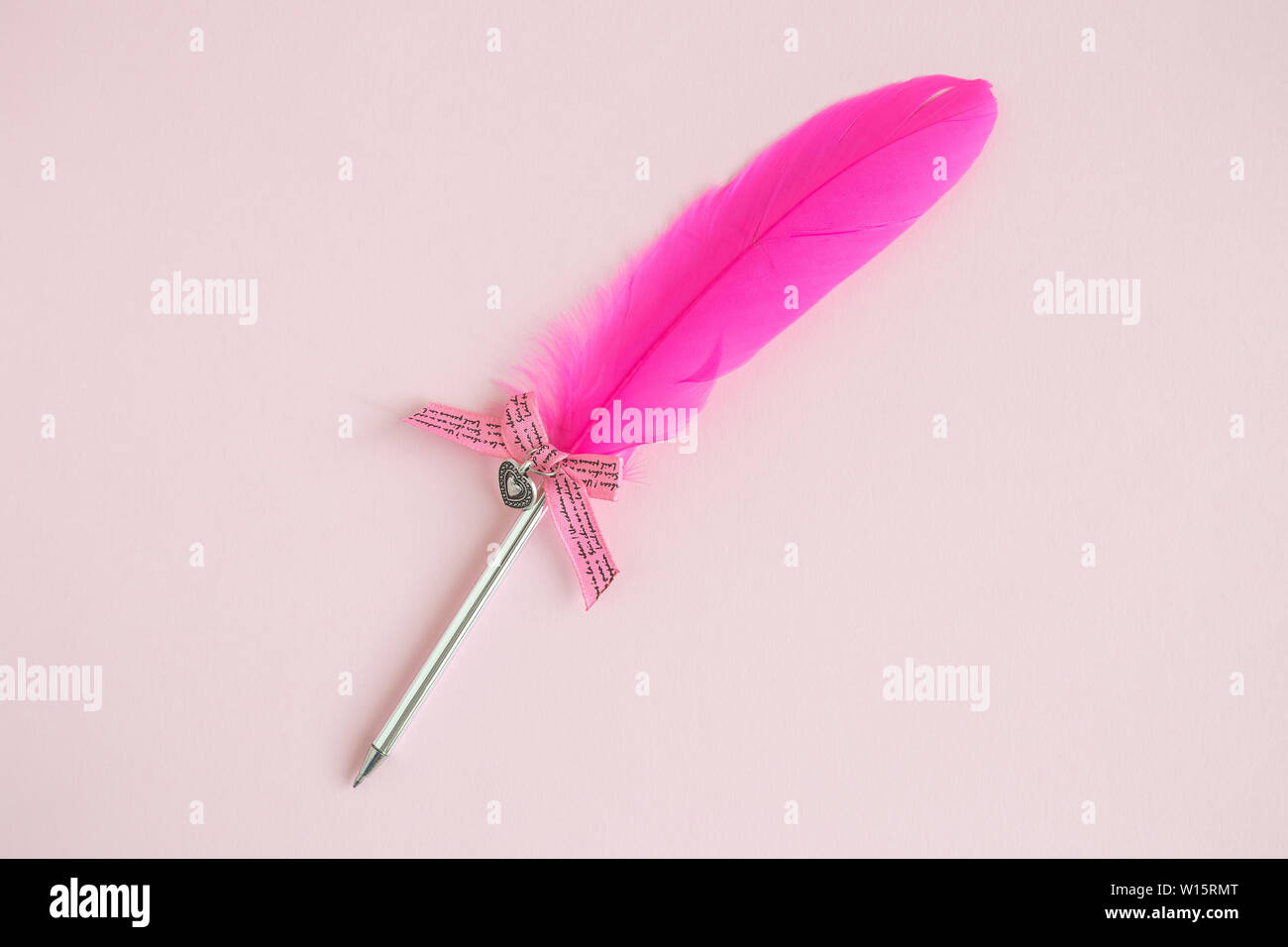 Piatto di laici feather pen contro rosa pastello sfondo. La scrittura di una lettera o di contattarci concetto. Foto Stock