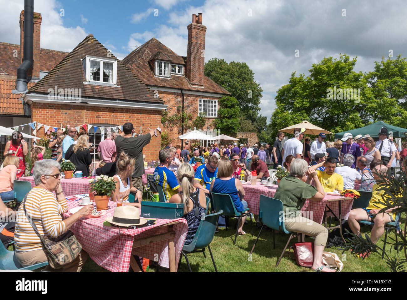 Un sacco di persone godendo di tè, bancarelle e intrattenimento a un villaggio inglese estate fete (fayre) in una giornata di sole in giugno Foto Stock