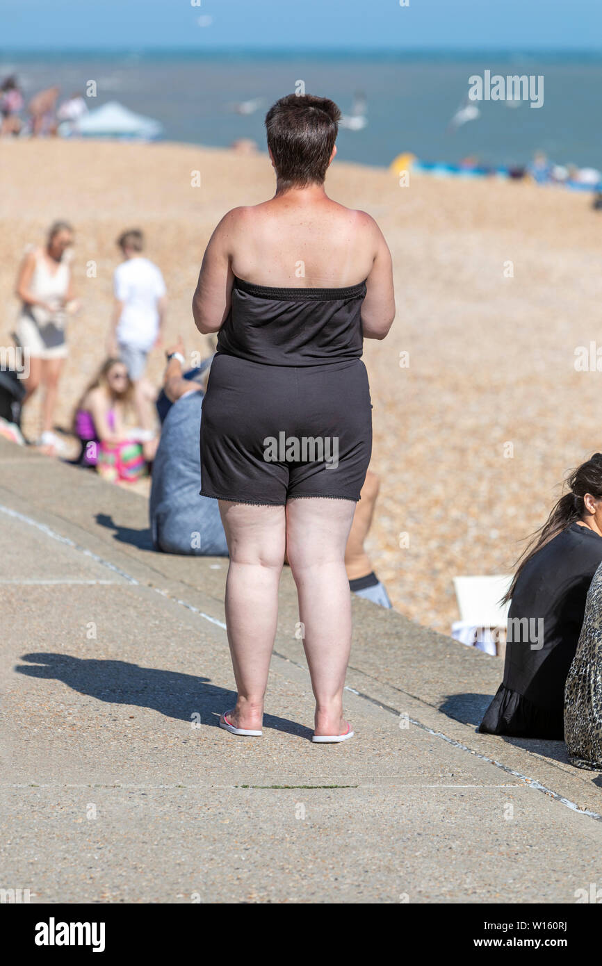 Una donna sovrappeso guardando una spiaggia Foto Stock