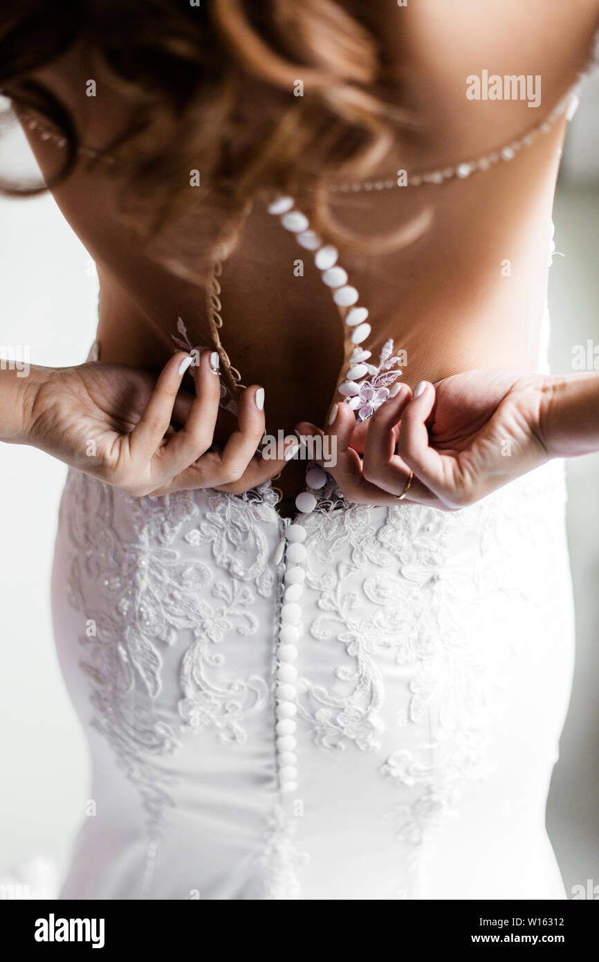 Sposa dal retro. Damigella zips l'abito da sposa. Foto Stock