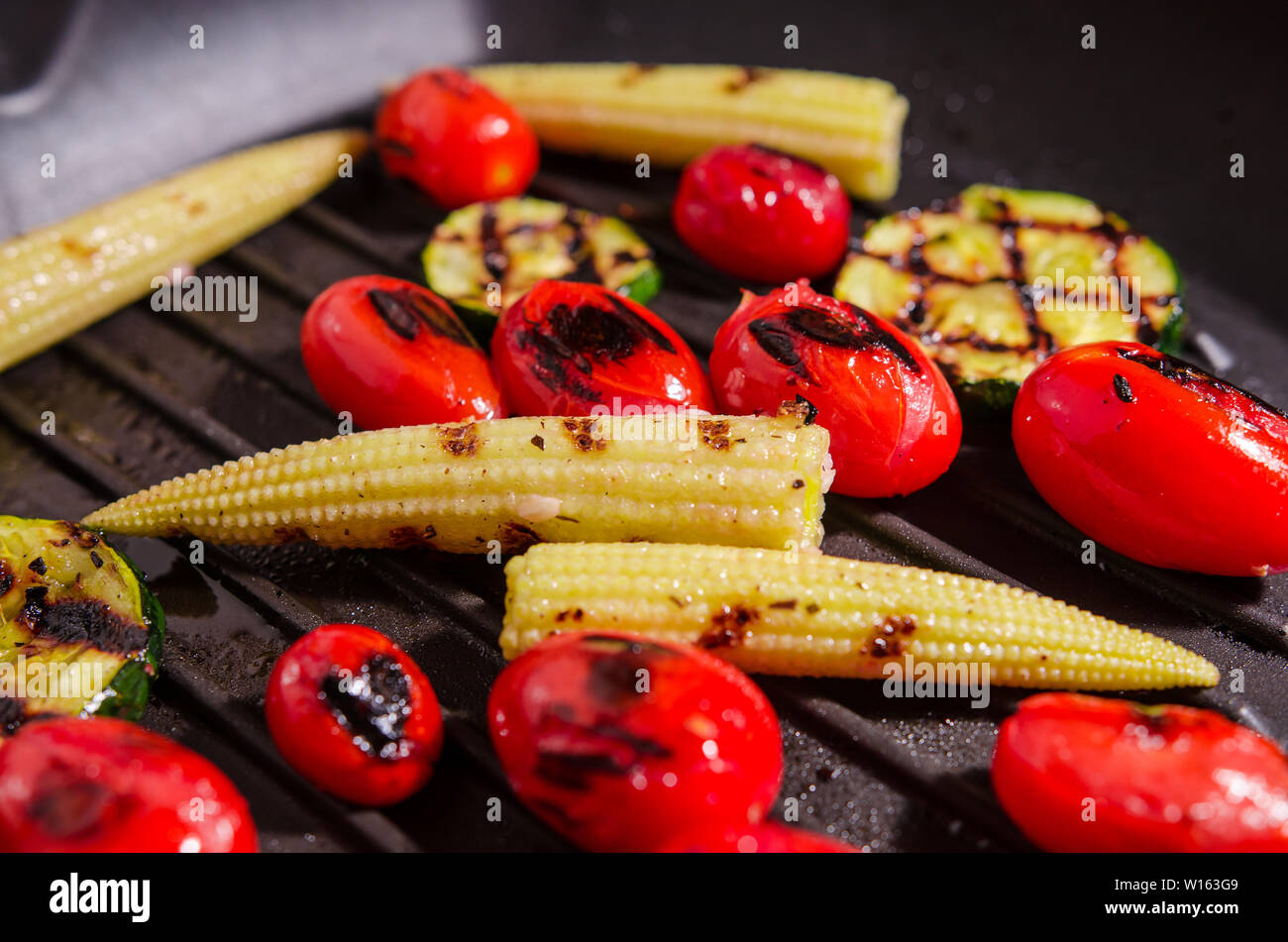 Grigliata di verdure - zucchine, baby mais, pomodoro ciliegino Foto Stock