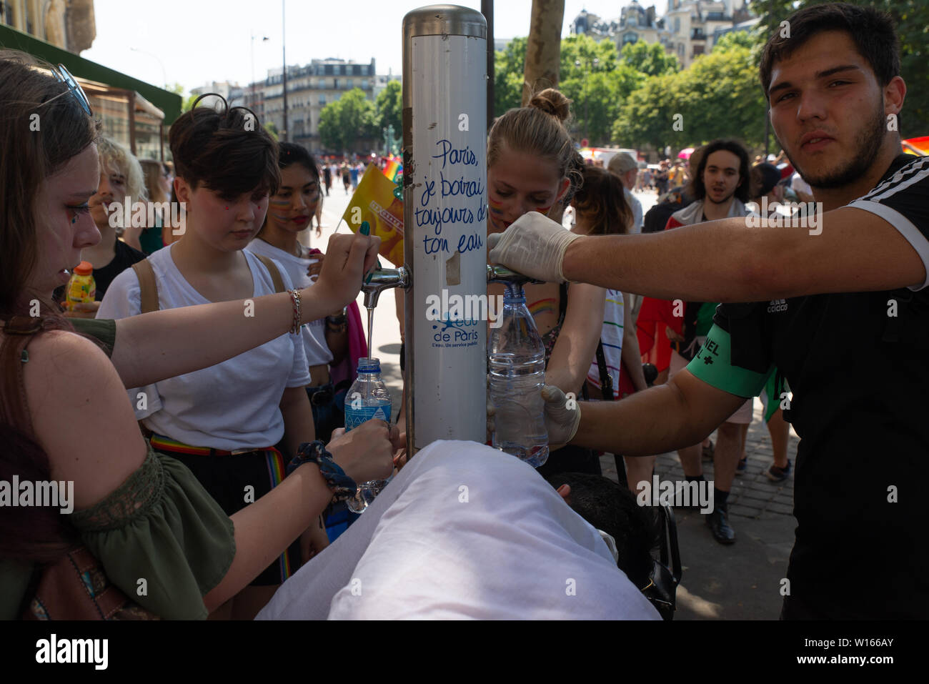 I partecipanti nella Parigi 2019 Gay Pride riempire le loro bottiglie di acqua durante uno di il giorno più caldo dell'anno. Foto Stock