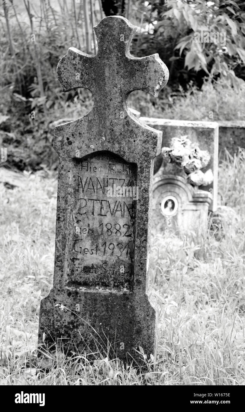 Ecka, Serbia - Giugno 2, 2019: Vecchia weathered crooked cristiane cattoliche tombestone al cimitero in bianco e nero Foto Stock