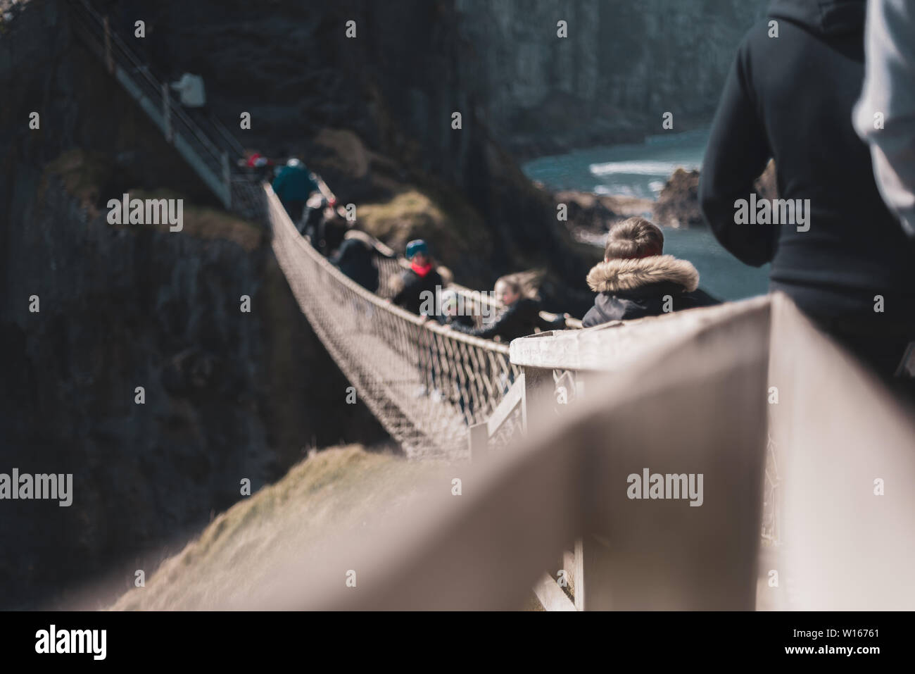 Irlanda del Nord, Regno Unito - 8° aprile 2019: spaventato i turisti attraversare il pericoloso ma bella Carrick-a-Rede ponte di corde Foto Stock