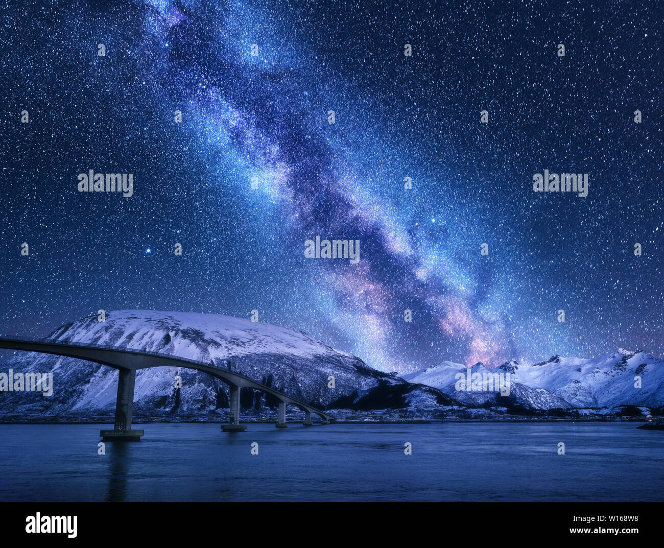 Ponte e cielo stellato con Via Lattea su montagne coperte di neve Foto Stock