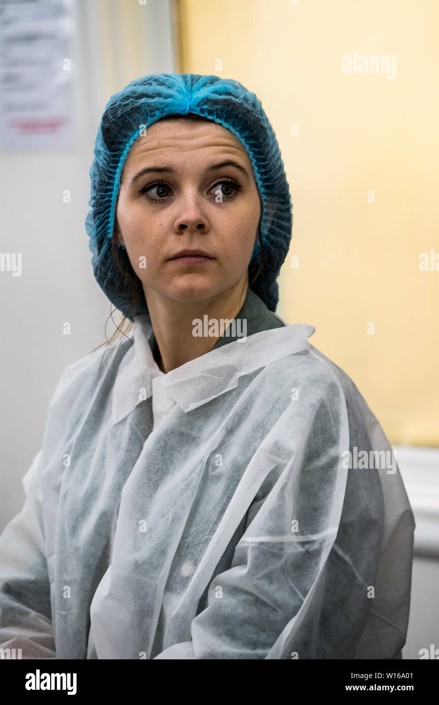 Una giovane donna che indossa indumenti protettivi visitando Quicke di formaggio, Devon, Regno Unito. Un tradizionale su piccola scala artigianale di latticini e formaggi maker Foto Stock