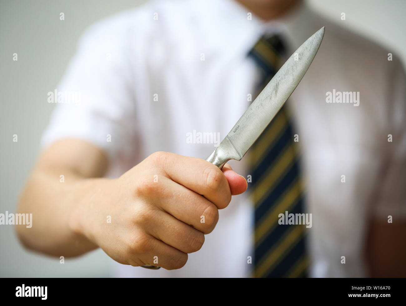 Scuola Teenage boy in possesso di un coltello a lama illustrano la criminalità in scuole nel Regno Unito Foto Stock