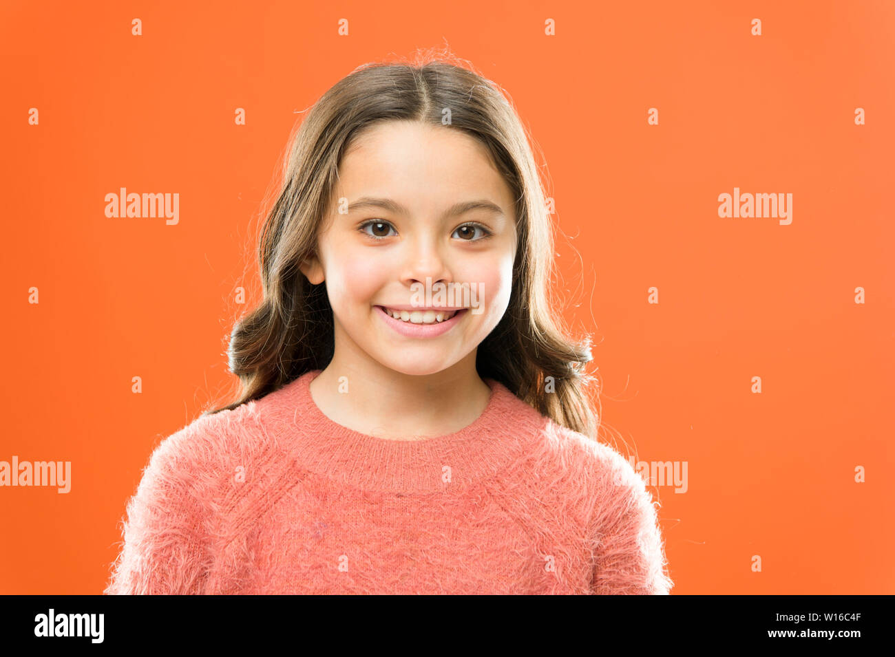 Cura del viso. La cosmetologia concetto di bellezza. Bambine viso carino sfondo arancione. Infanzia felice. Prodotti per la cura del bambino e psicologia. Il benessere e la salute. La felicità radiante. Bambini sorridenti vicino. Foto Stock