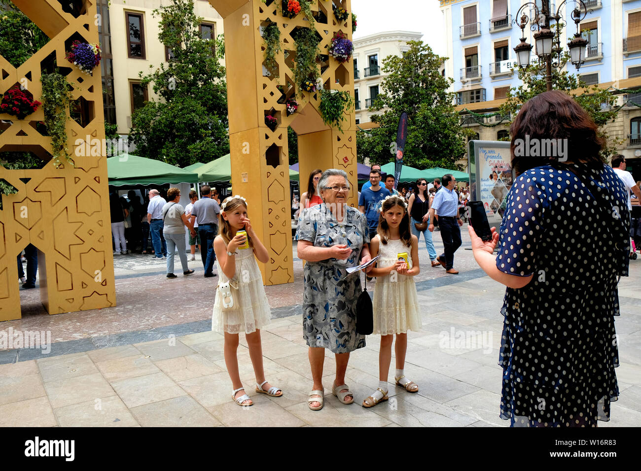 Gemello ragazze e alla loro nonna guardando la madre in una piazza in Granada, Spagna; tre generazioni: nipoti, la nonna e la mamma. Foto Stock