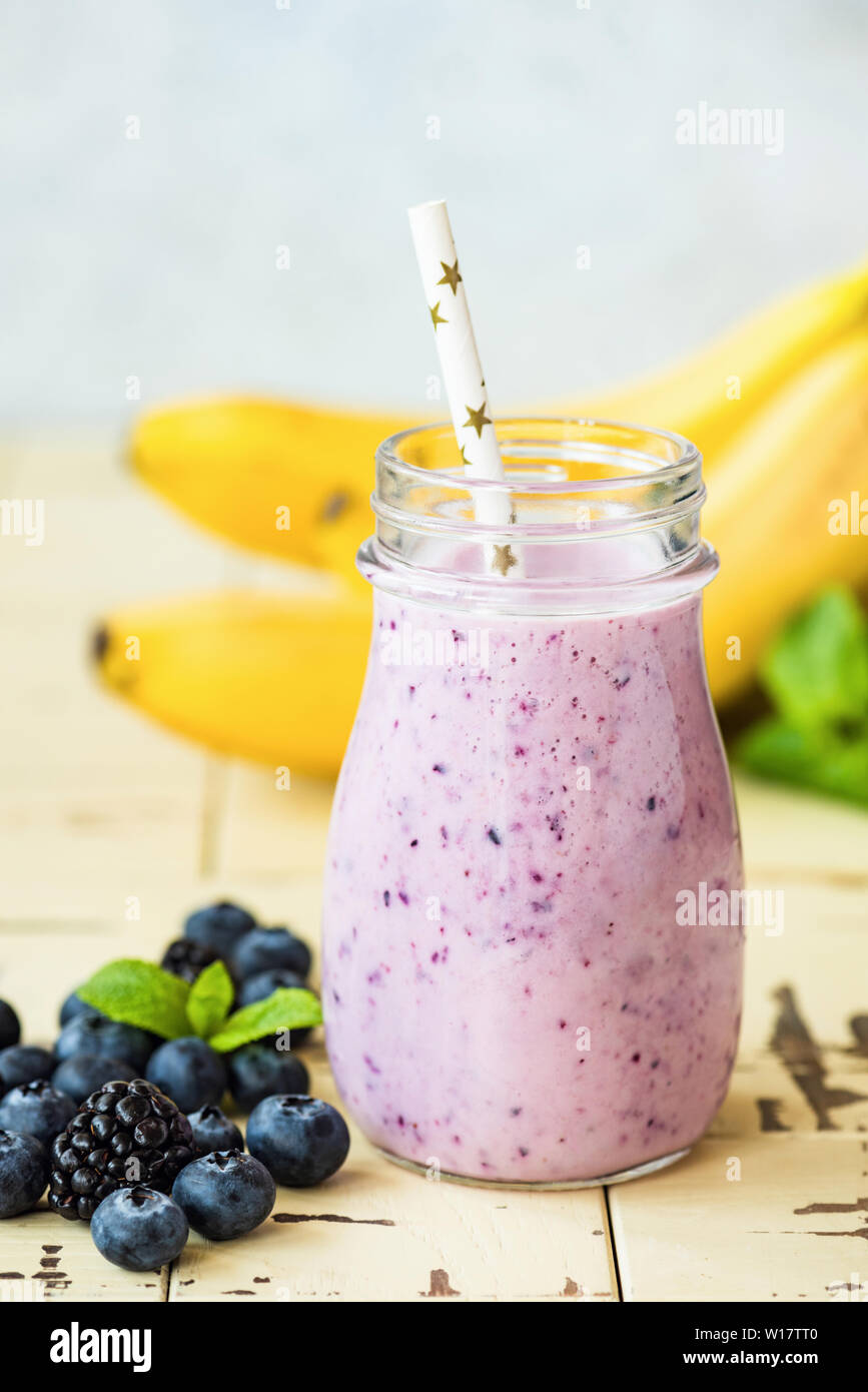 Una sana berry smoothie banana in vetro con cannuccia. Orientamento verticale. Frullato viola Foto Stock