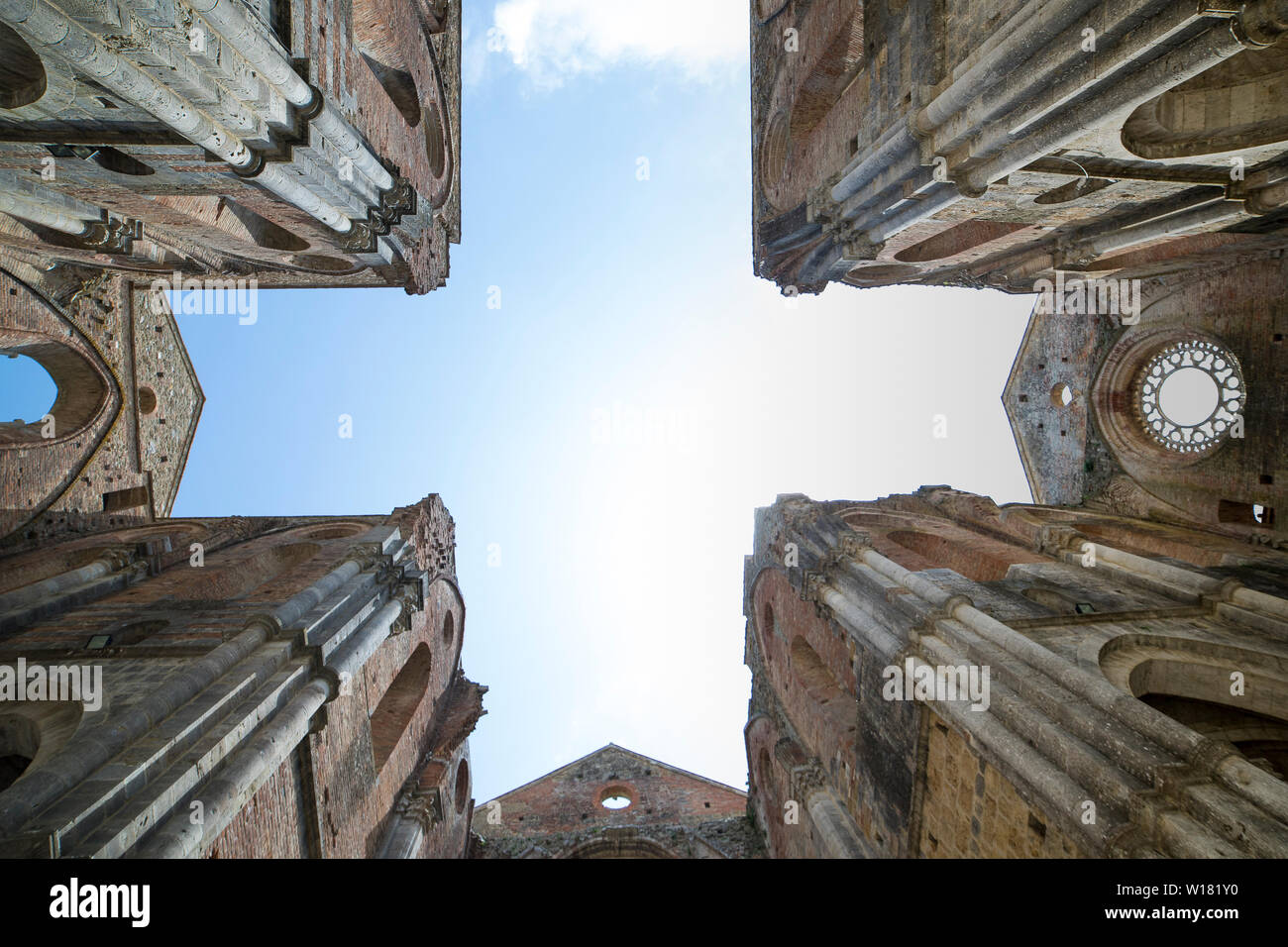 Dal basso verso l'alto vista scoperchiata abbazia di San Galgano con pareti che forma a croce nel cielo. Chiusdino, Toscana, Italia. Foto Stock