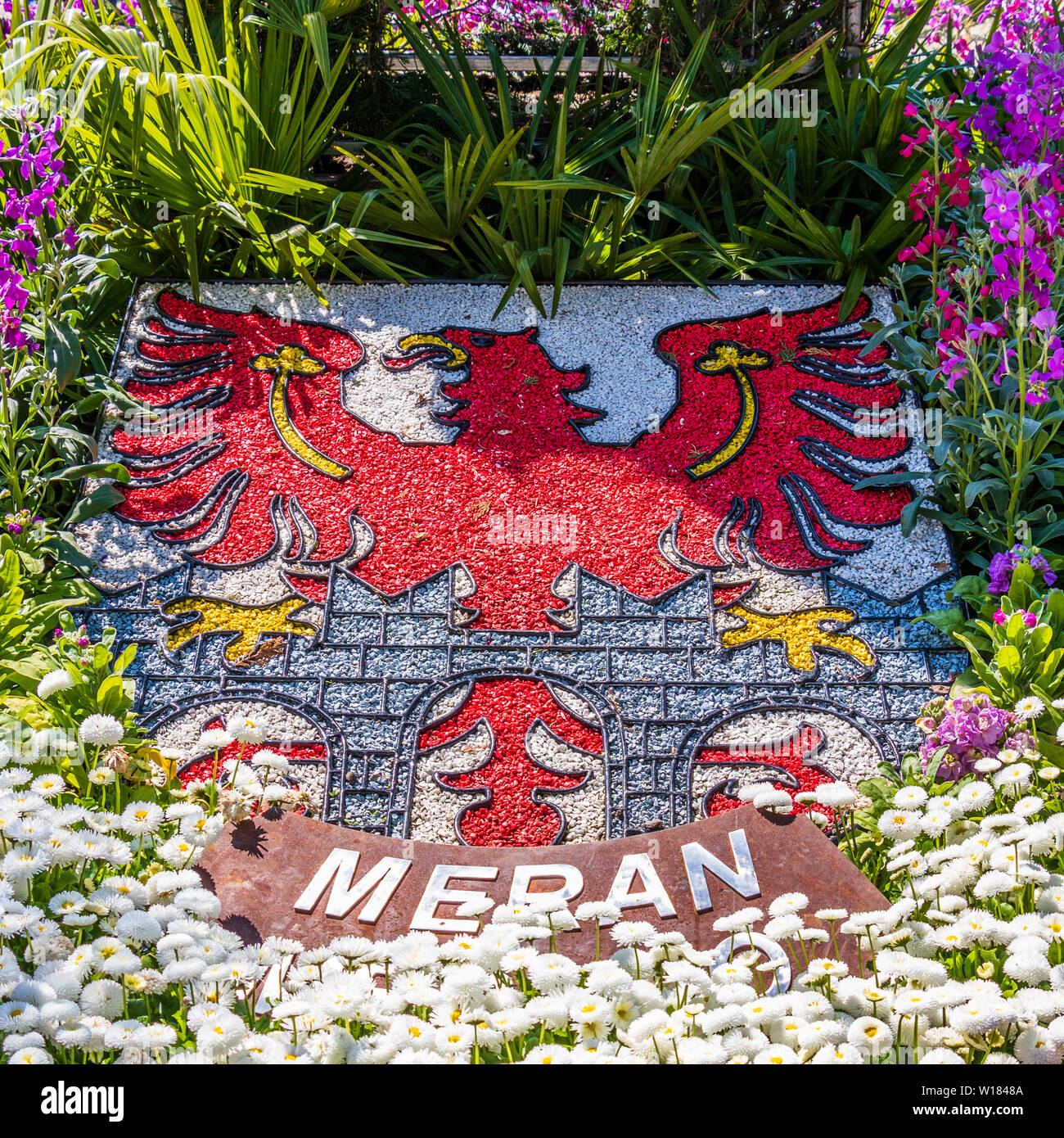 Cresta naturale, emblema, Bandiera della città di Merano in aiuola di fiori e vegetazione. La città di Merano. Provincia di Bolzano, Alto Adige, Italia. L'Europa. Foto Stock