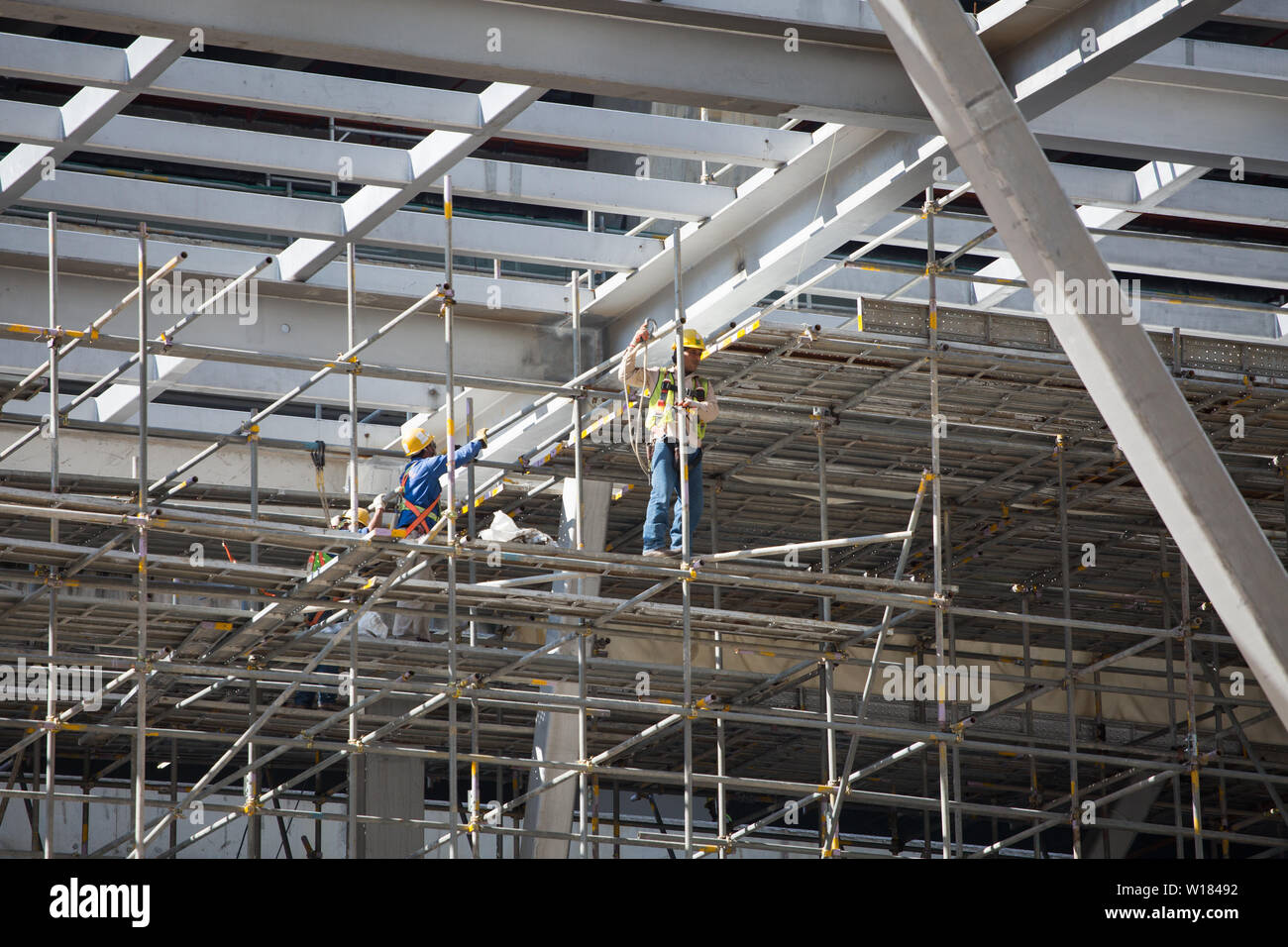 Operaio edile su una impalcatura allacciamento della linea di sicurezza. Foto Stock