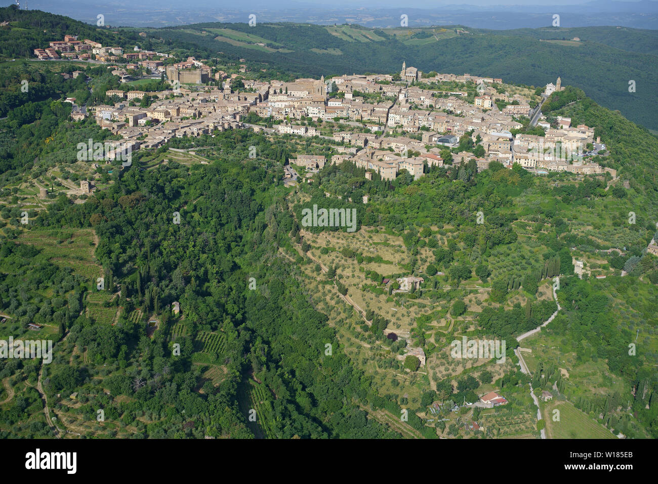VISTA AEREA. Pittoresca cittadina medievale in cima a una collina in Val d'Orcia. Montalcino, Provincia di Siena, Toscana, Italia. Foto Stock