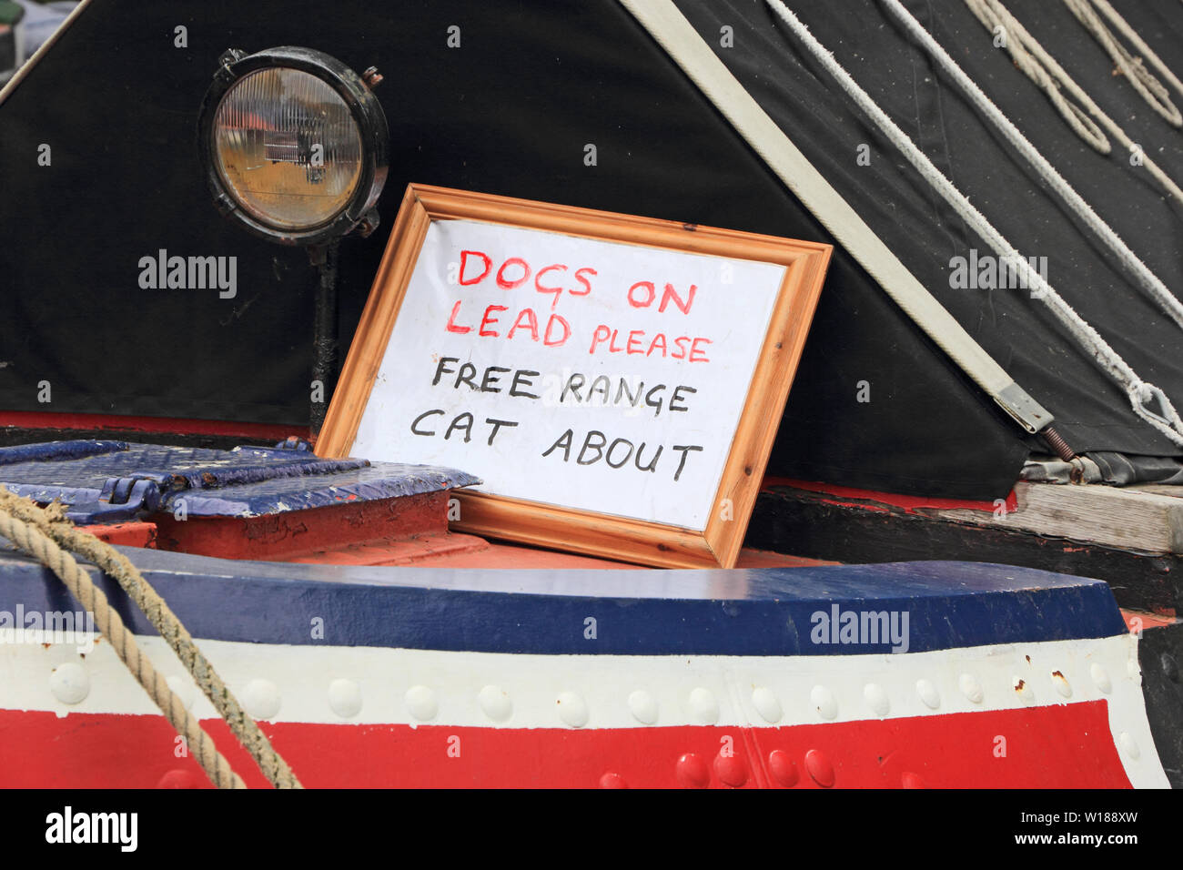 'Dogs sul piombo si prega, intervallo libero cat circa il segno sul canal boat stretta. Foto Stock