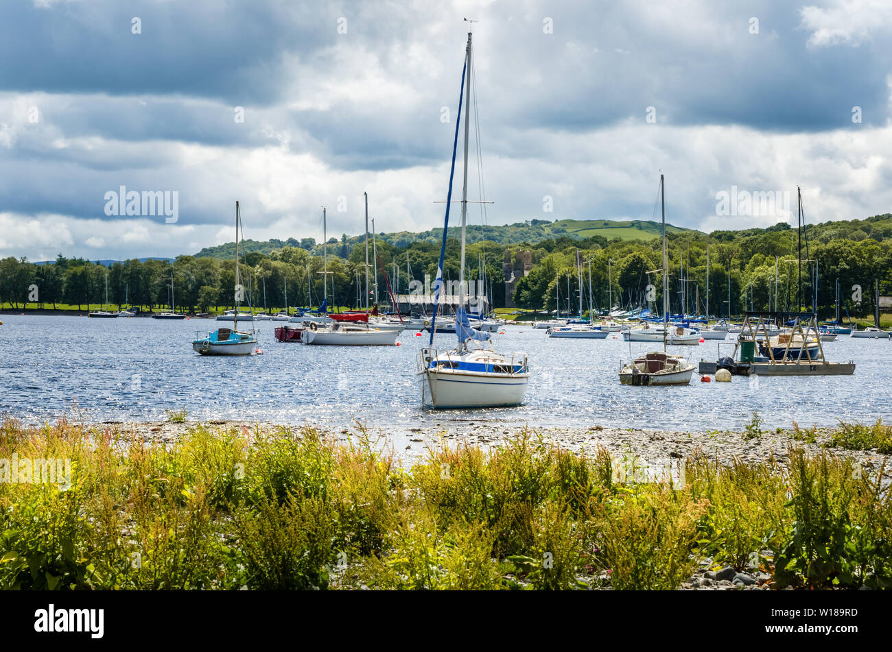 Barche a vela ancorate vicino alla riva di un bellissimo lago di un nuvoloso giorno di primavera Foto Stock