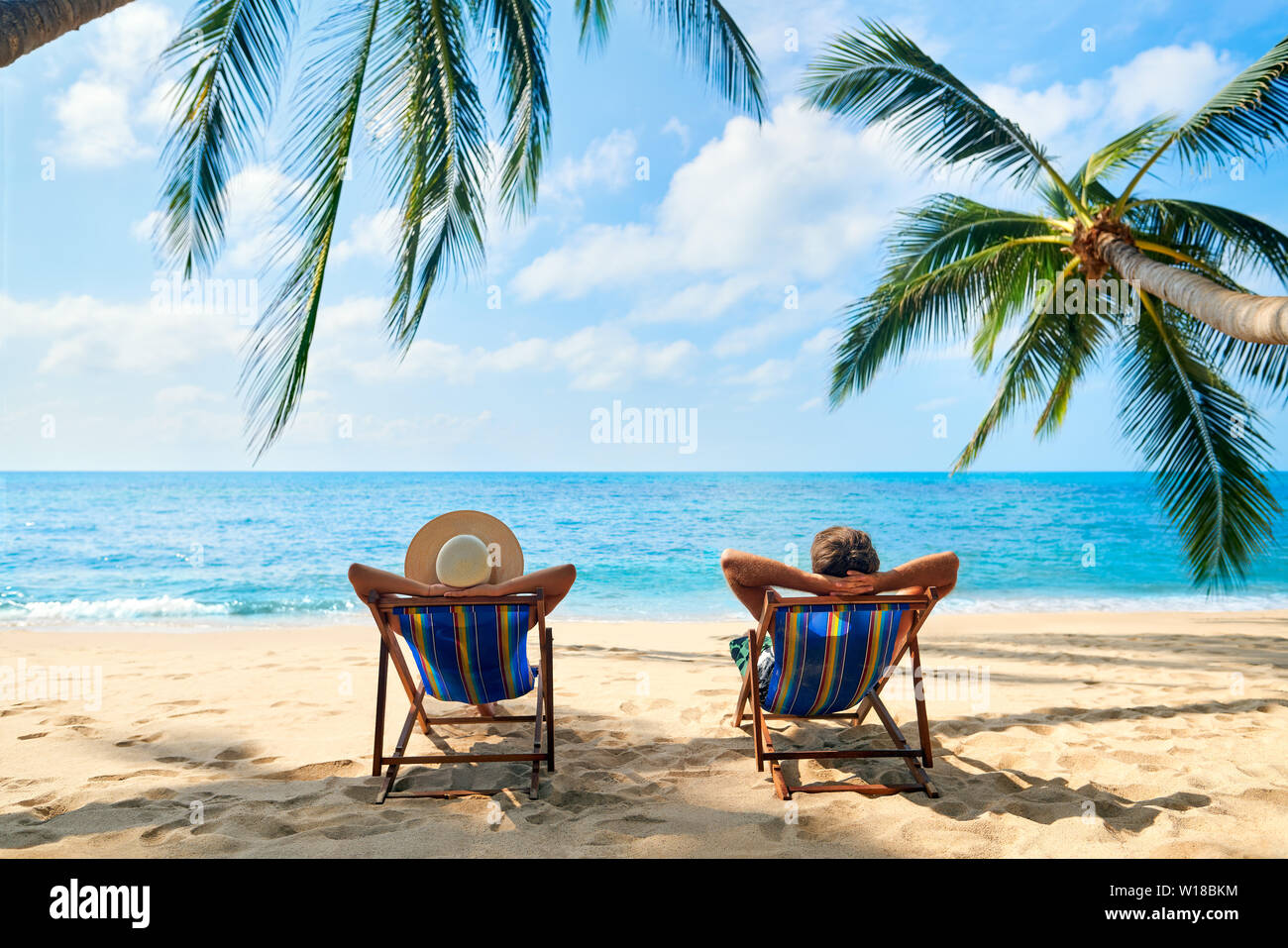 Paio di rilassarsi sulla spiaggia godere del bel mare sull'isola tropicale. Estate spiaggia Concetto di vacanza Foto Stock