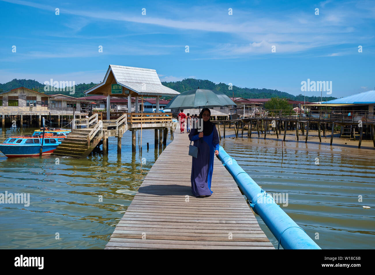 Persone wallking lungo uno dei principali percorsi di legno che portano in acqua stilt village Kampong Ayer in Bandar Seri Begawan , Brunei. Foto Stock