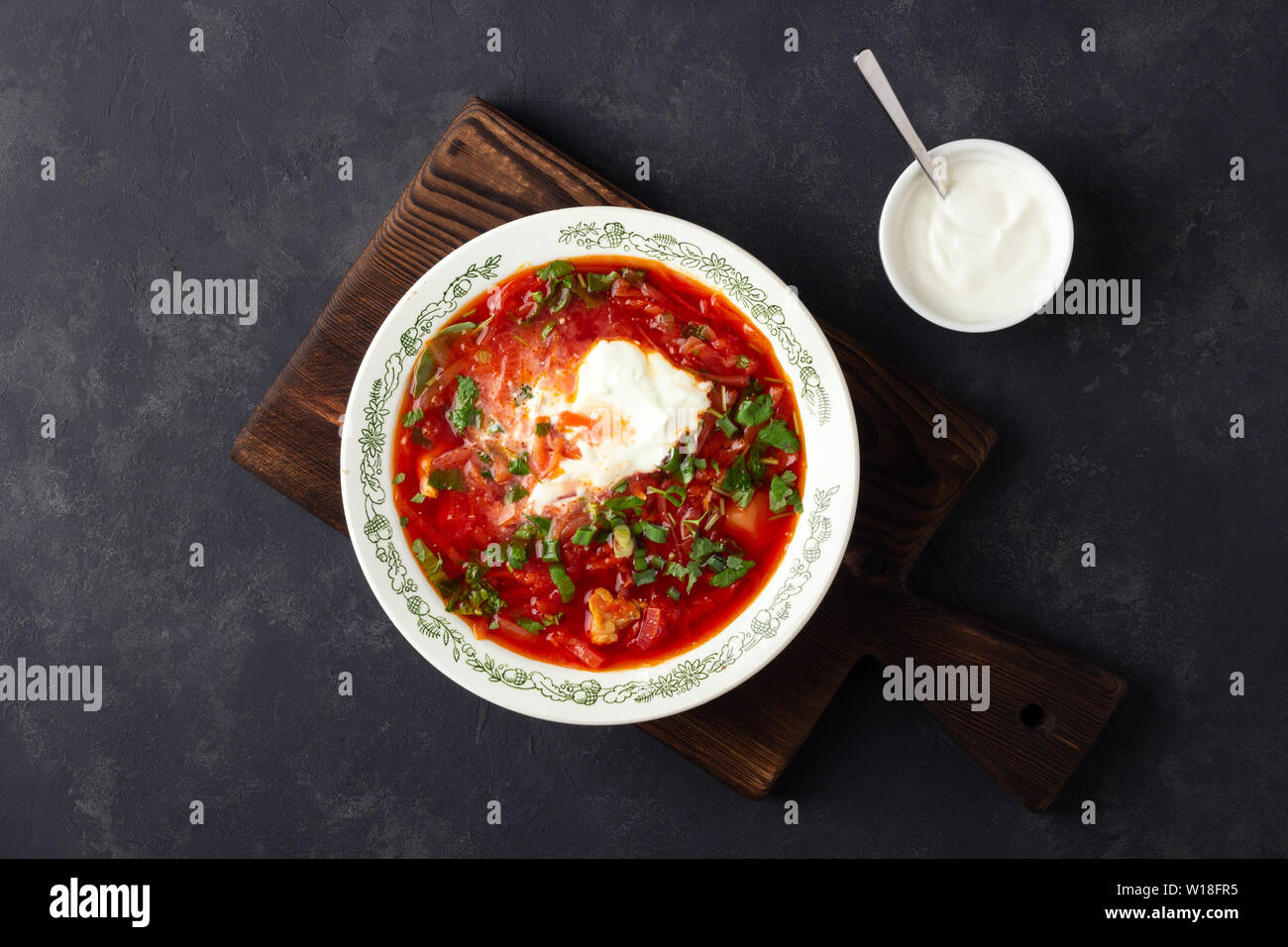 Tradizionale russo ucraino barbabietole tradizionale zuppa rossa - borscht con panna acida sulla pietra nera dello sfondo. Vista dall'alto. Foto Stock