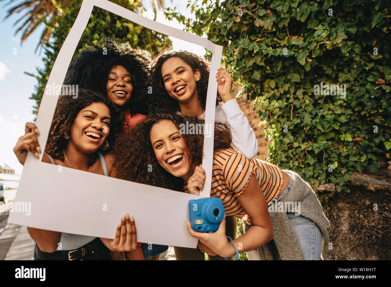 Un gruppo di giovani amici di sesso femminile in posa con vuoto cornice immagine. Ragazze sorridenti con vuoto photo frame all'aperto nella città. Foto Stock