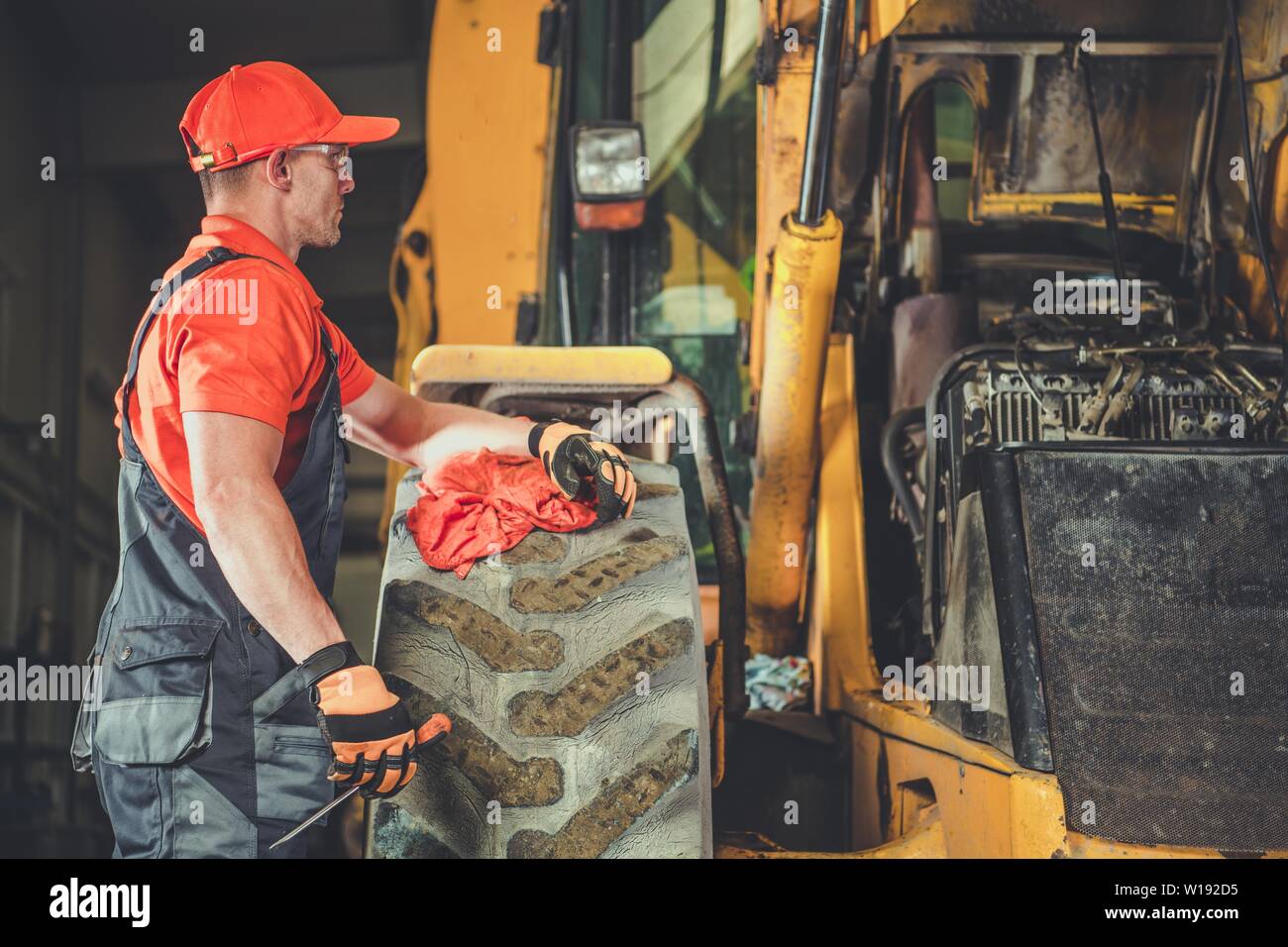 Trattore piccolo Bulldozer Riparazione del motore. Caucasian meccanico professionista e il suo lavoro. Attrezzature pesanti Centro di Servizio. Foto Stock