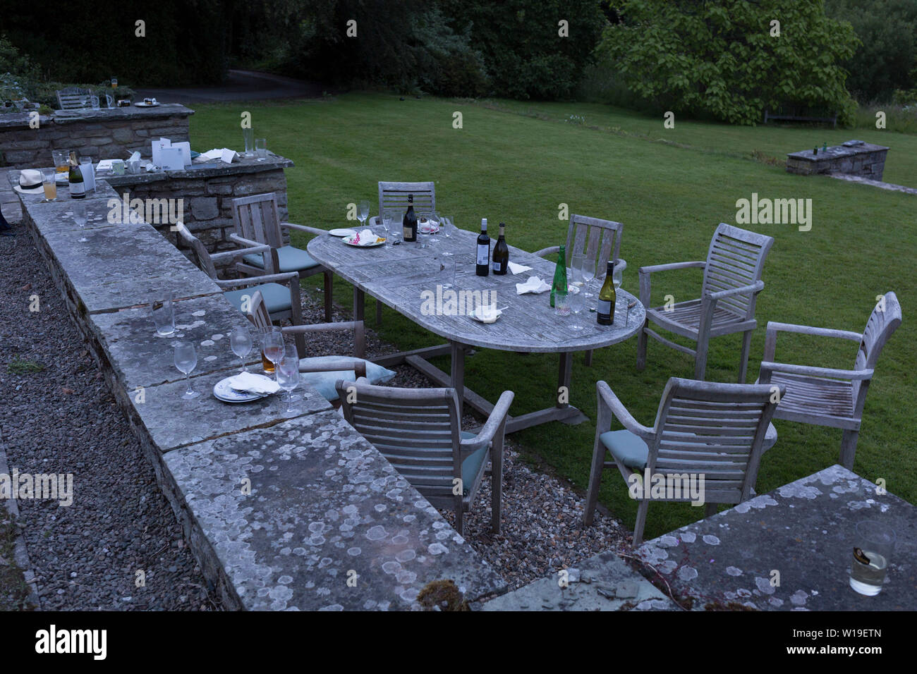 I postumi residui di bicchieri, bottiglie e le piastre all'alba, la mattina dopo un cinquantesimo compleanno, sparsi intorno al giardino nell'Herefordshire campagna, il 23 giugno 2019, a Kington, Herefordshire, Inghilterra. Foto Stock