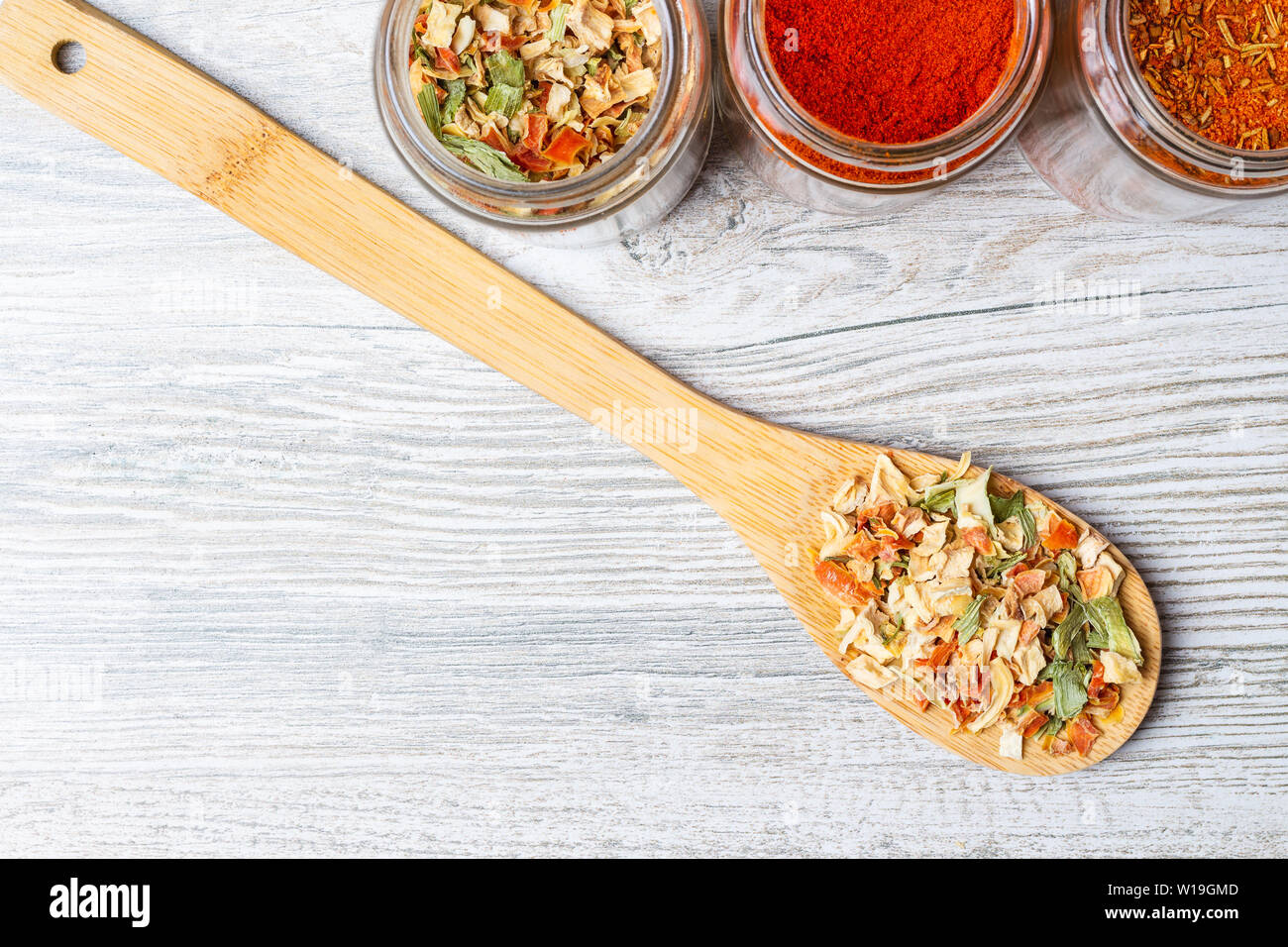 Spezie e liofilizzata verdure sul bancone della cucina. I vasetti con spezie e verdure essiccate su un cucchiaio di legno. Foto Stock