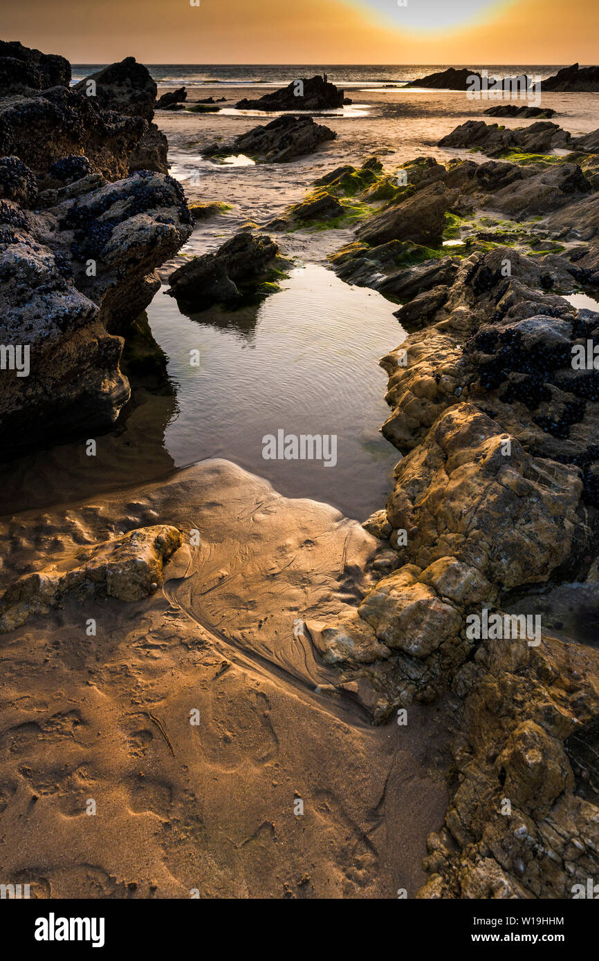 Pool di rocce al tramonto su Fistral Beach in Newquay in Cornovaglia. Foto Stock