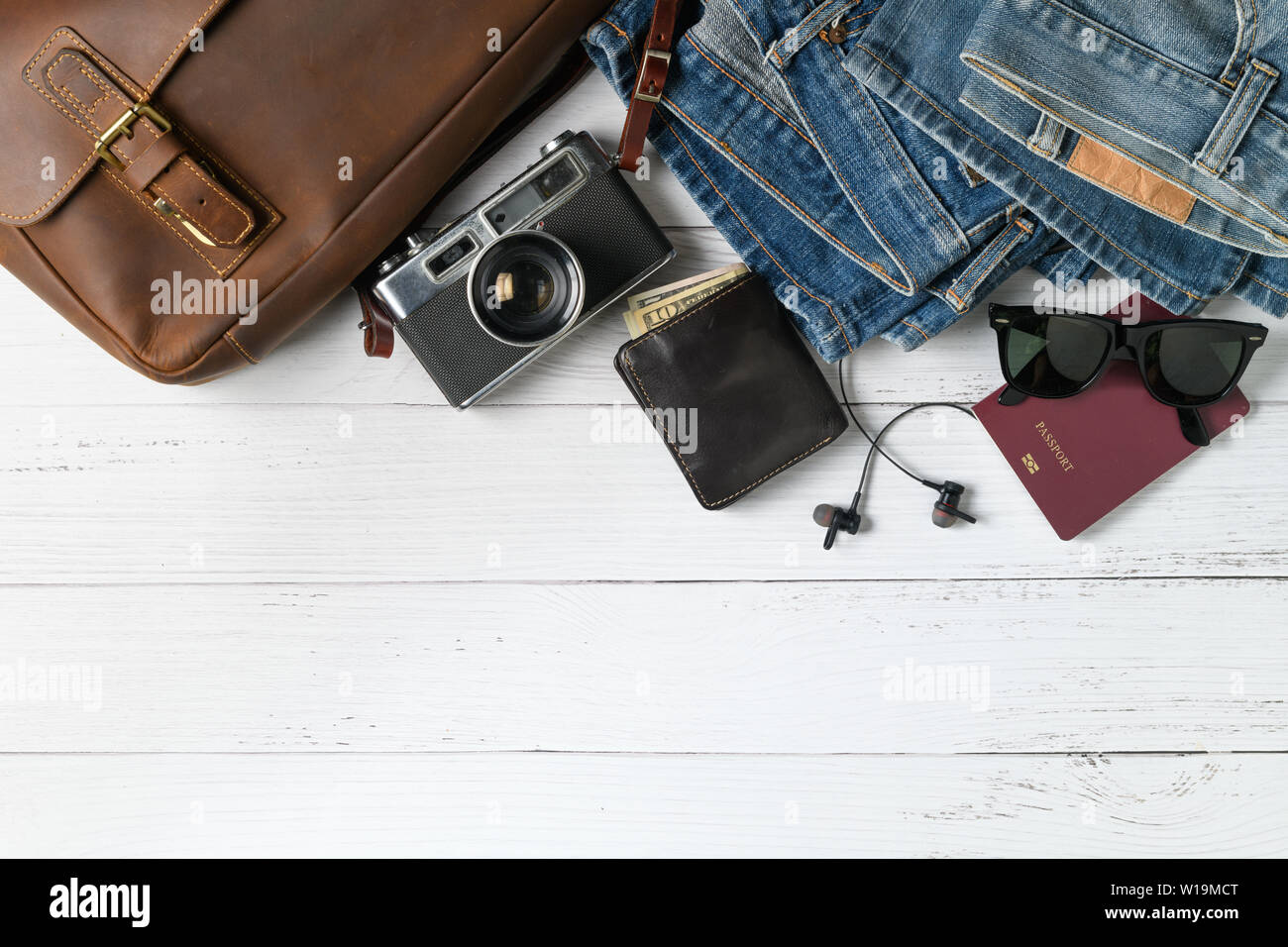 Accessori per piano di viaggio, viaggio vacanze, turismo - vintage borsa in pelle e vecchi jeans su uno sfondo di legno. Appartamento di laici e di spazio di copia Foto Stock
