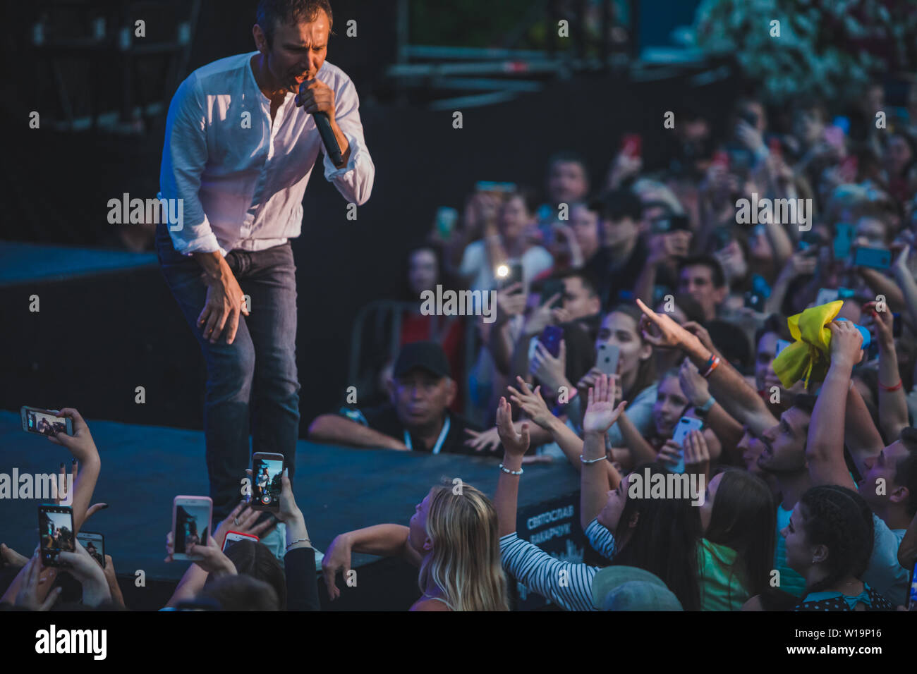 LVIV, Ucraina - 18 Giugno 2019: rock band cantante sul palco con microfono si affollano intorno Stadio riprese su telefoni. music fest Foto Stock