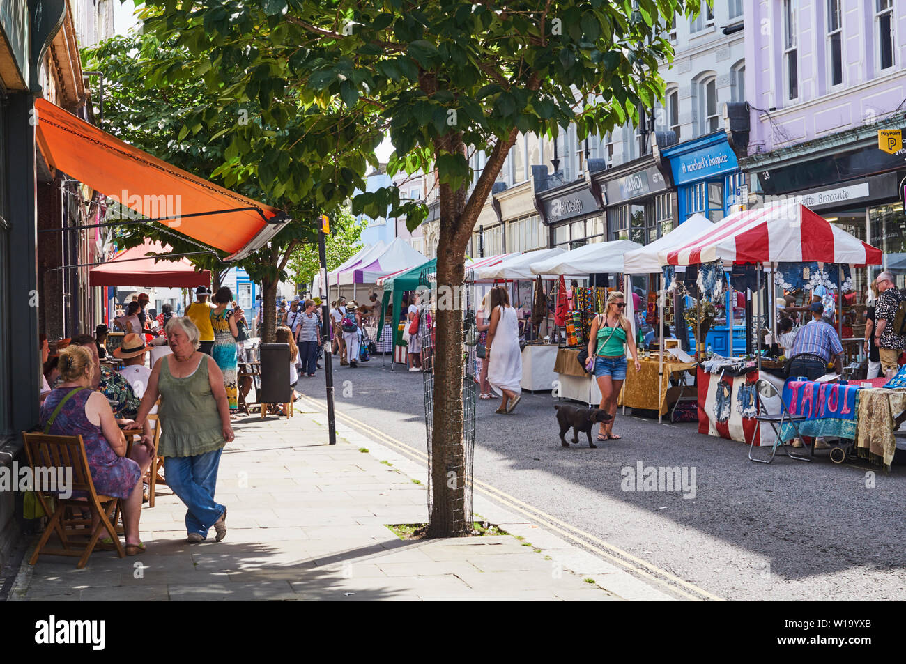 Le persone al di fuori di un caffè e la visita di Kings Road street market, nella cittadina di St Leonards on Sea, East Sussex, Regno Unito Foto Stock