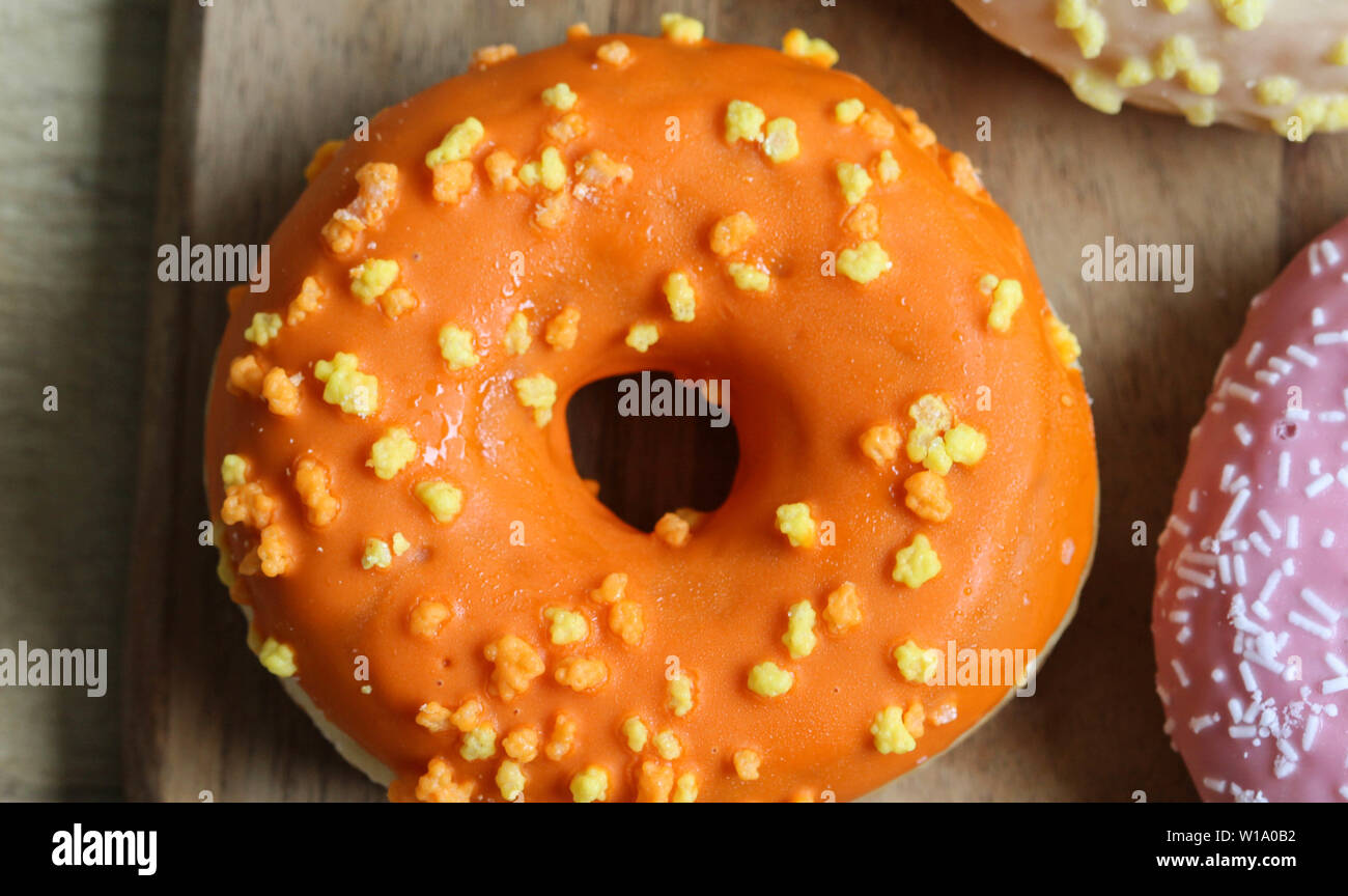Close up di un singolo orange ciambella con spruzza su uno sfondo di legno Foto Stock