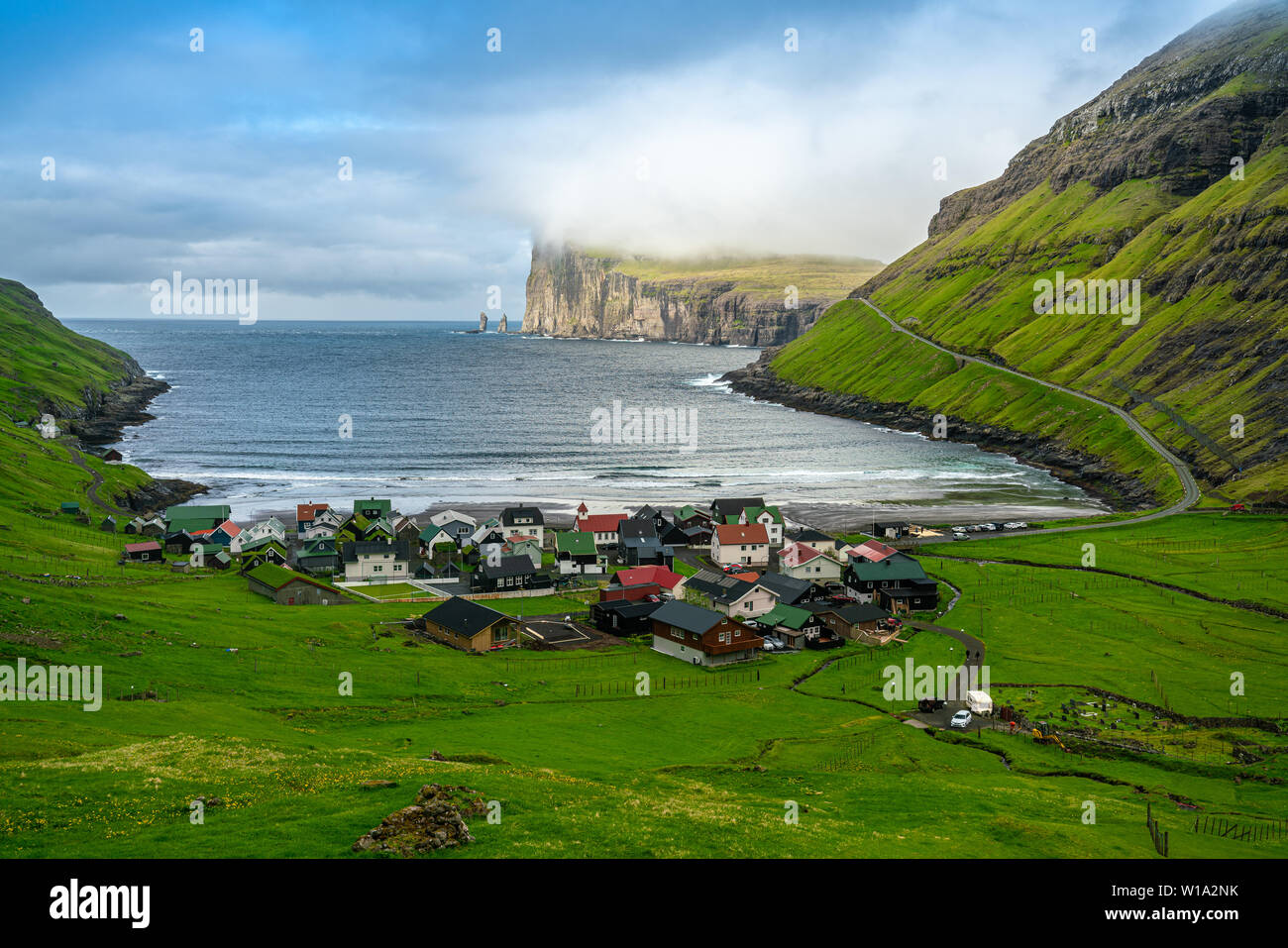 Tjornuvik villaggio e la spiaggia con il gigante e la Strega mare pile rocce, Isole Faerøer Foto Stock
