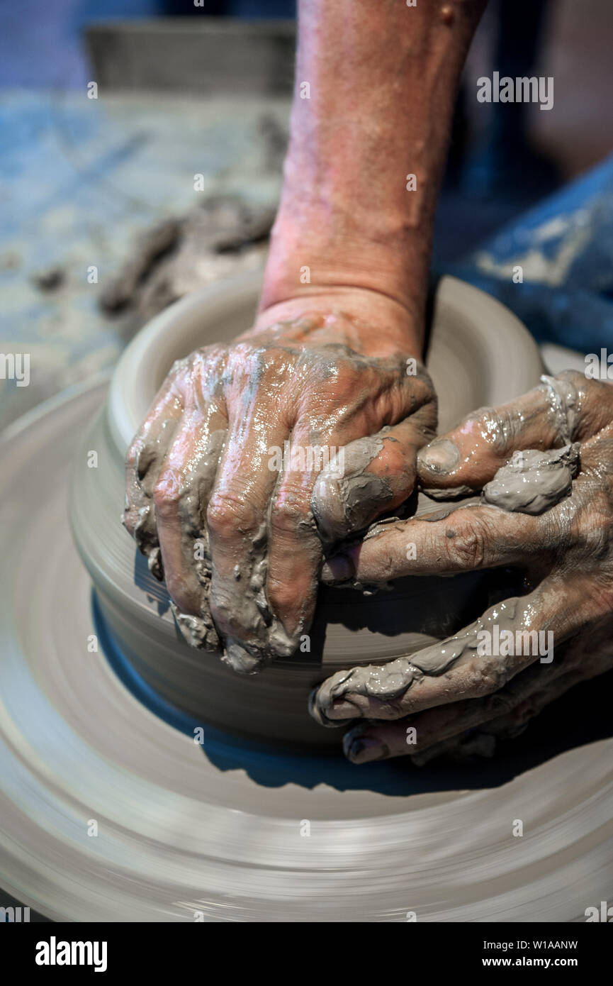 Potter a lavorare sulla ruota di ceramiche (close up mani e argilla grigia) Foto Stock