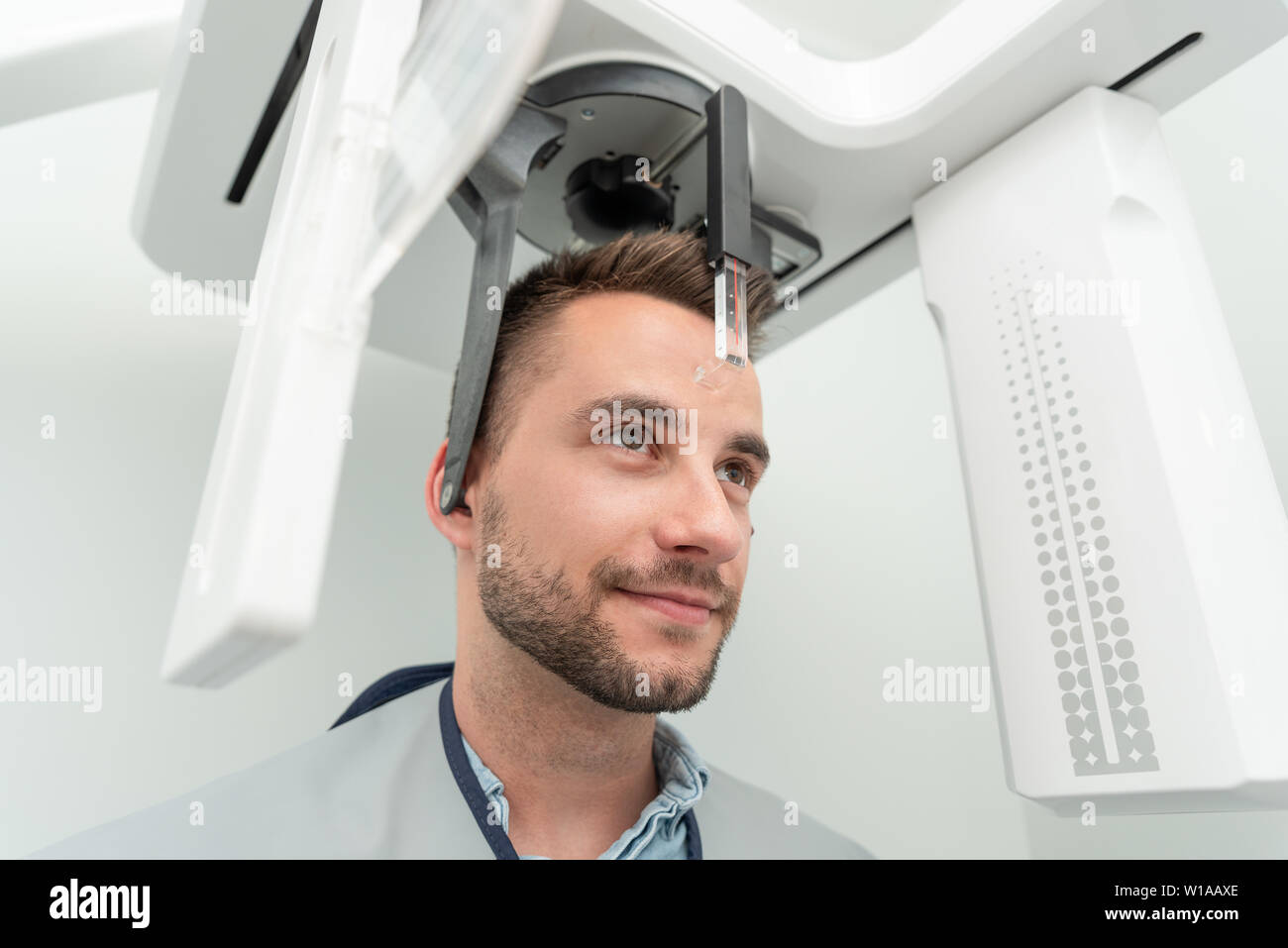 Bel uomo paziente in piedi nella macchina a raggi x. Radiografia panoramica di professional dental clinic. Foto Stock