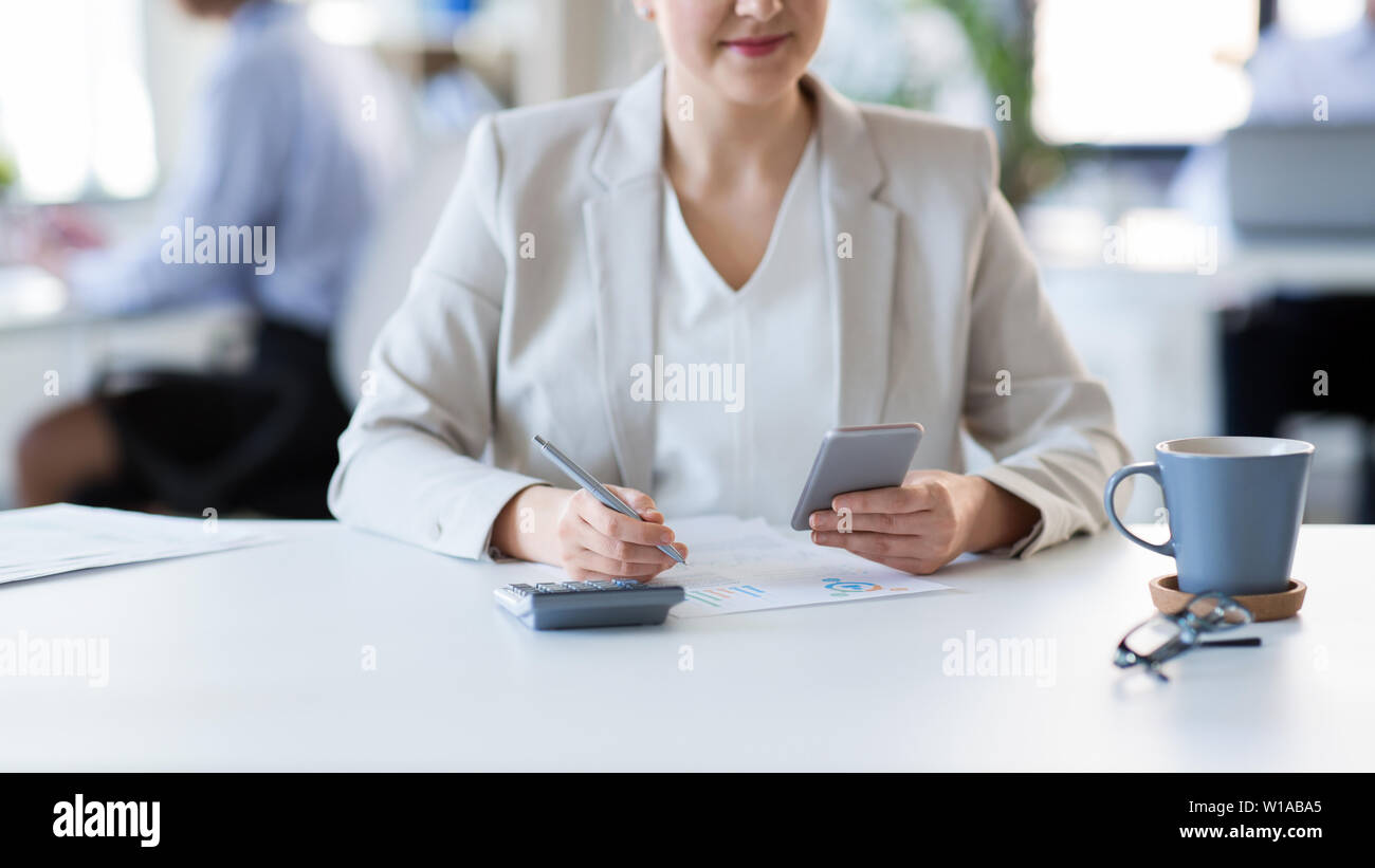 Imprenditrice con lo smartphone lavorando in ufficio Foto Stock