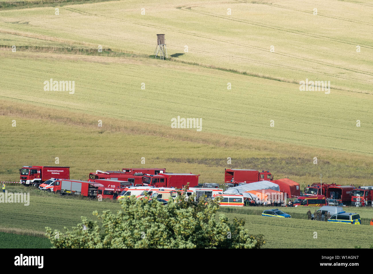 Aerzen, Germania. 01 Luglio, 2019. Numerosi vigili del fuoco dei veicoli di emergenza e numerose ambulanze sono in piedi in un campo vicino al sito del crash di un elicottero Bundeswehr. La Bundeswehr ha confermato il crash di un elicottero di formazione in Bassa Sassonia. La Eurocopter EC 135 macchina si è schiantato intorno a 2 p.m. vicino Dehmcurbrock, circa 30 chilometri a ovest di Hameln, ha detto un portavoce della Bundeswehr all'Agenzia Tedesca di Stampa il lunedì. C'erano stati due persone a bordo. Il velivolo appartiene alla International Helicopter Training Center a Bückeburg. Credito: Swen Pförtner/dpa/Alamy Live News Foto Stock