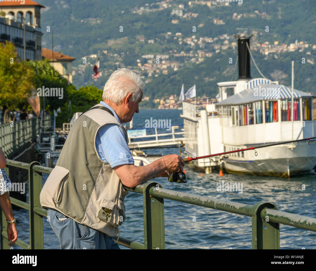 Il LAGO DI COMO, Italia - Giugno 2019: Persona pesca dalla riva del lago in Cadenabbia sul Lago di Como. Foto Stock