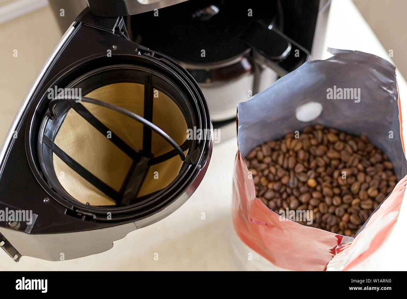 Cestello del filtro per caffè, drip-tipo macchina per il caffè e i chicchi di caffè sul tavolo della cucina, vista dall'alto. Riutilizzabili in mesh metallico filtro di caffè. Accessori per caffè Foto Stock