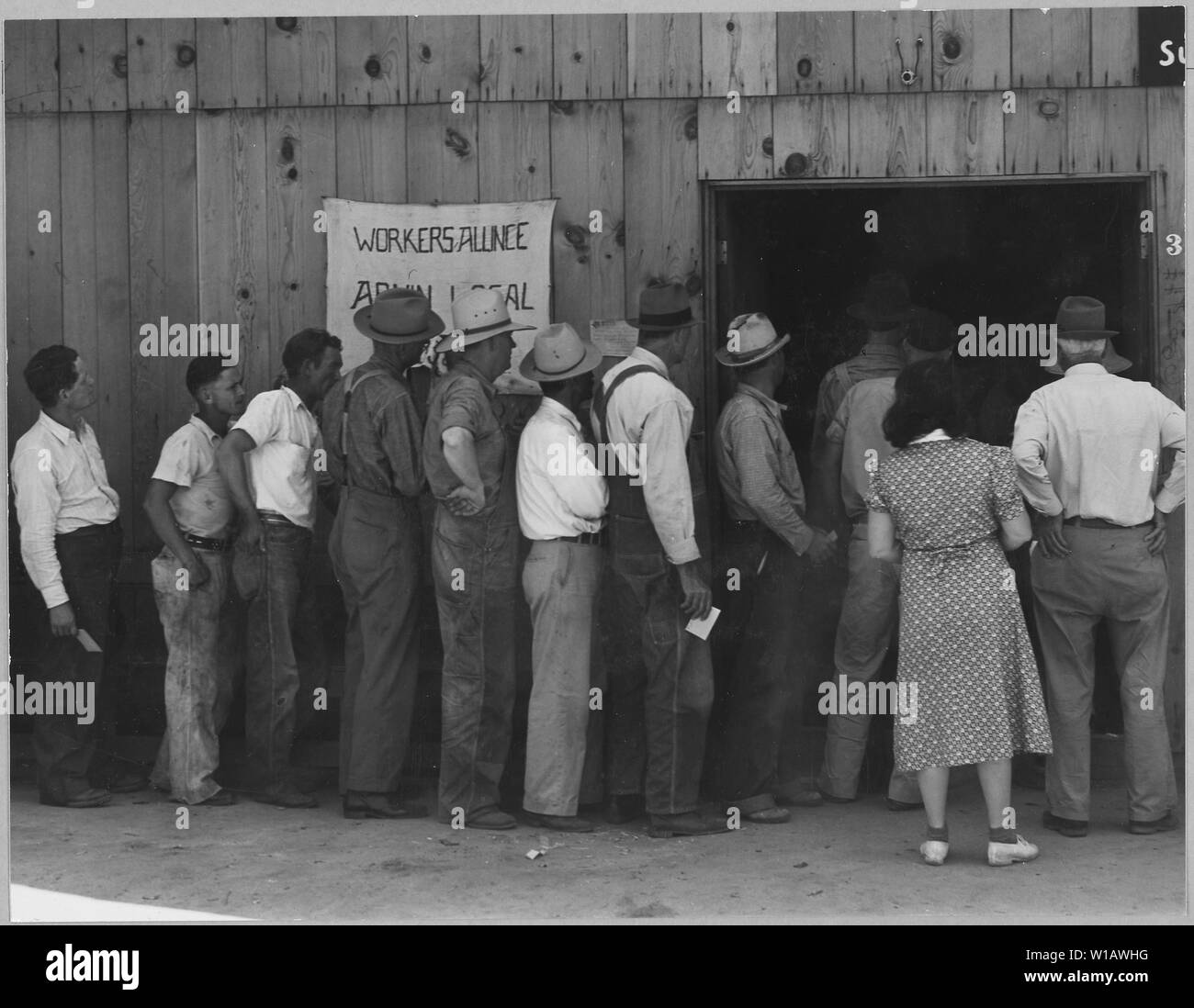 Arvin, Kern County, California. Line up per rilievo di stato il giorno di paga. Mostra l'esterno dell'edificio. Questo b . . .; Portata e contenuto: Full didascalia recita come segue: Arvin, Kern County, California. Line up per rilievo di stato il giorno di paga. Mostra l'esterno dell'edificio. Questo edificio è utilizzato per il lavoratore's alliance riunioni, Chiesa di Cristo i servizi e la sede centrale per la distribuzione dei controlli S.R.A.. Questa è una zona della rapida crescita shacktown europee la maggior parte dei client di sfiato raffigurata qui abitano questi nuovi baraccopoli rurale. Foto Stock