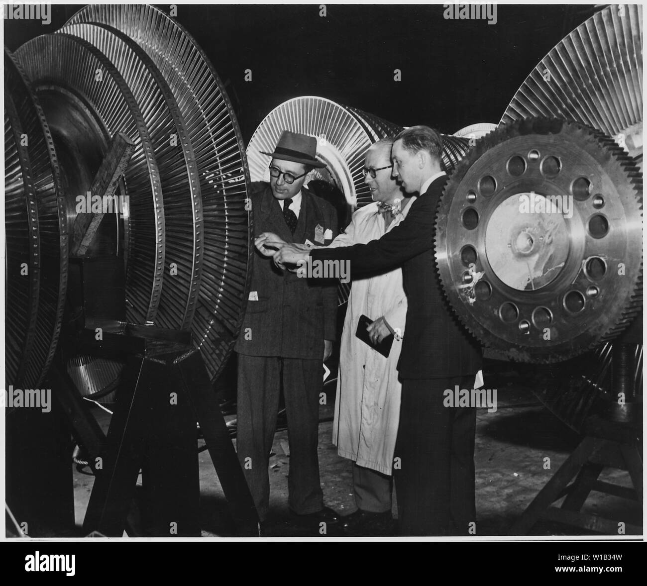 Il Belgio. Belga di ingegneri elettrici Georges Jean L. van Antro, sinistra, Georges H. Marchal, centro e Jacques de Schaetzen, ispezionare il rotore di un 40.000 chilowatt turbina durante la loro visita alla General Electric Company è di nuovo $30,000,000 turbina edificio di produzione a Schenectady, New York Foto Stock