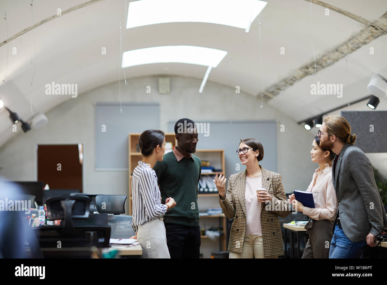 Multi-etnico gruppo di gente di affari di parlare durante la pausa caffè in ufficio sorridendo allegramente mentre, spazio di copia Foto Stock