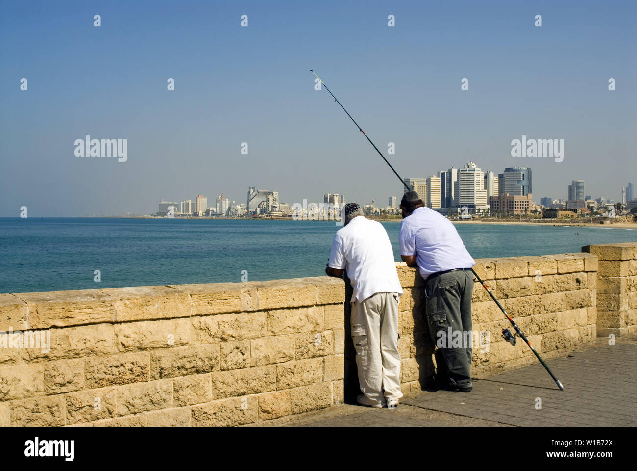 Pesca due uomo in piedi poggiano sulla parete contro Tel Aviv vista Foto Stock