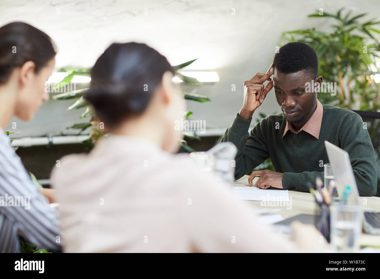 Multi-etnico gruppo di gente di affari occupato a lavorare durante la riunione in ufficio, concentrarsi su African American uomo, spazio di copia Foto Stock