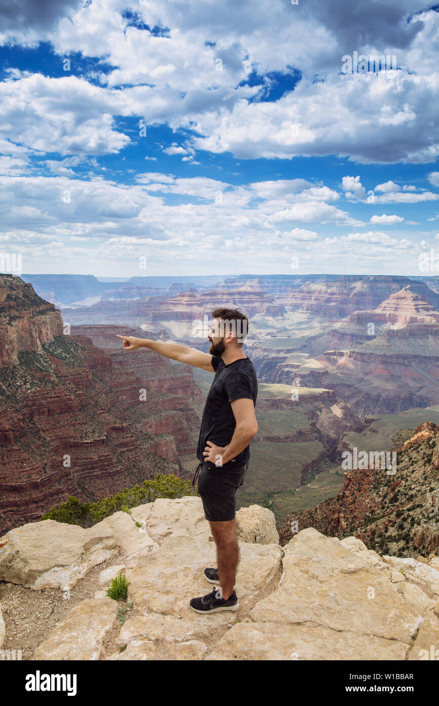 Uomo turistico vicino ad una scogliera in South Rim puntando il dito e il braccio verso il canyon, il Parco Nazionale del Grand Canyon, Arizona, Stati Uniti d'America Foto Stock