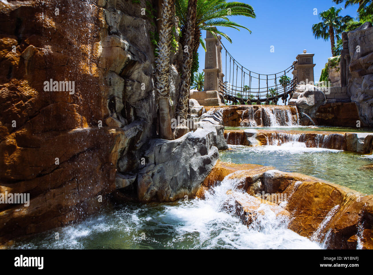 Cascate e ponte oscillante nei motivi del Mandalay Bay Resort & Casino vista attraverso un arco, Las Vegas, Nevada, STATI UNITI D'AMERICA Foto Stock