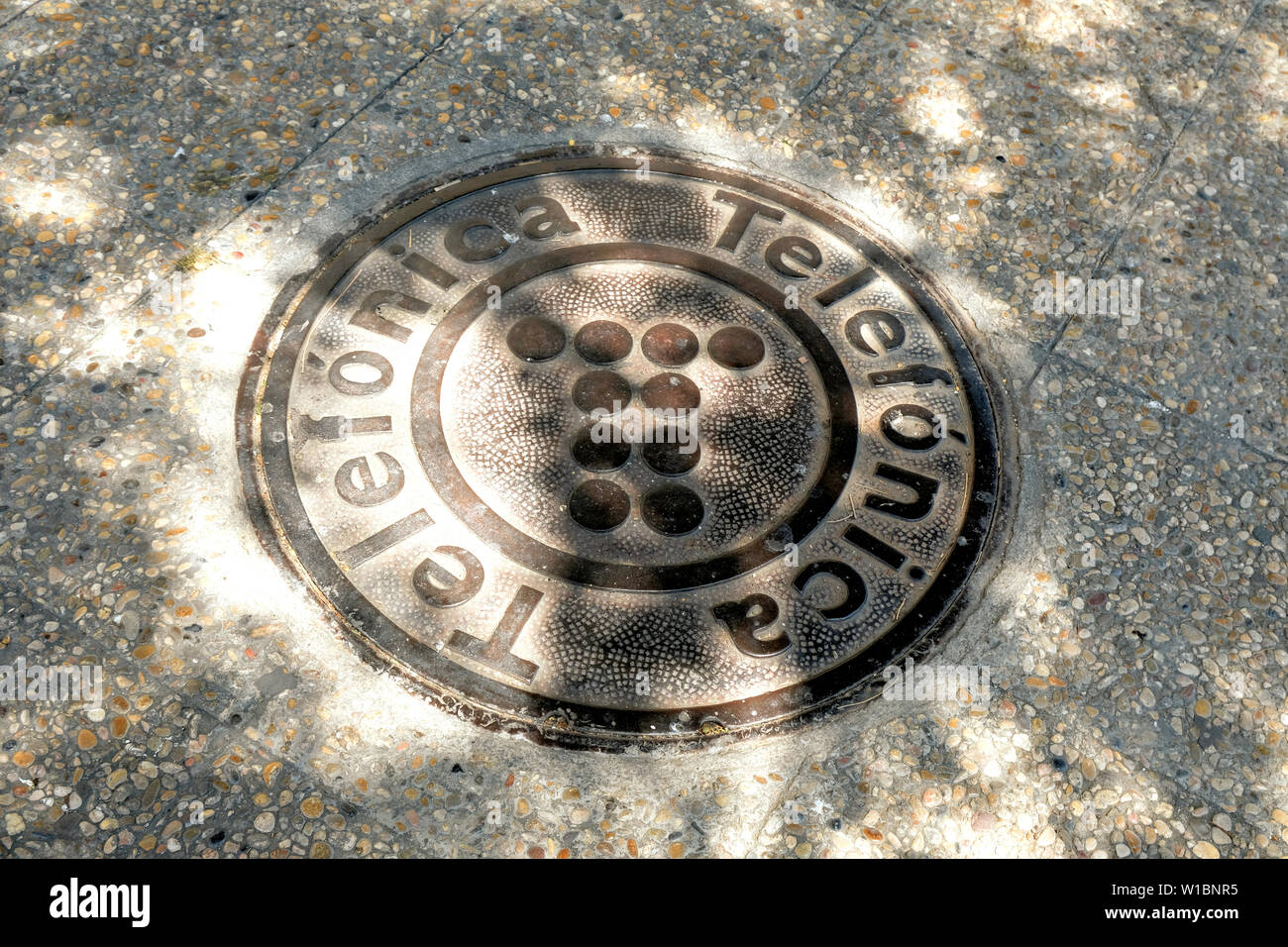 Telefónica ghisa chiusino con il logo su un marciapiede ombreggiato in Granada, Spagna. Foto Stock