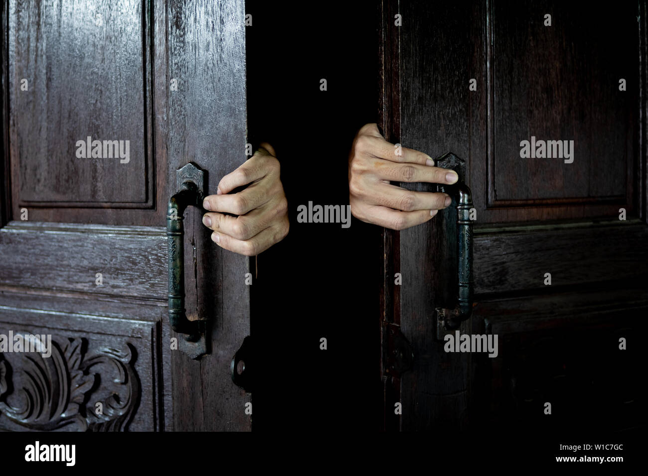 Le mani per aprire la porta di legno dall'interno della camera oscura. Foto Stock